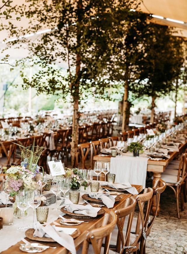 Hochzeitstafel unter dem Zelt mit Holzstühlen und Blumendeko, GS EVENTS